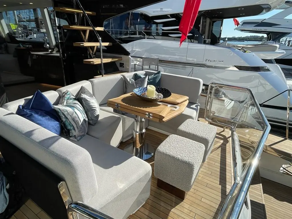 Luxury yacht seating area featuring plush sofas, a wooden table with a candle, and modern design elements.